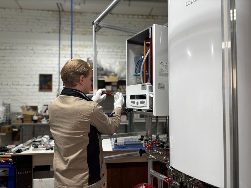 A heating technician inspecting and repairing a boiler system