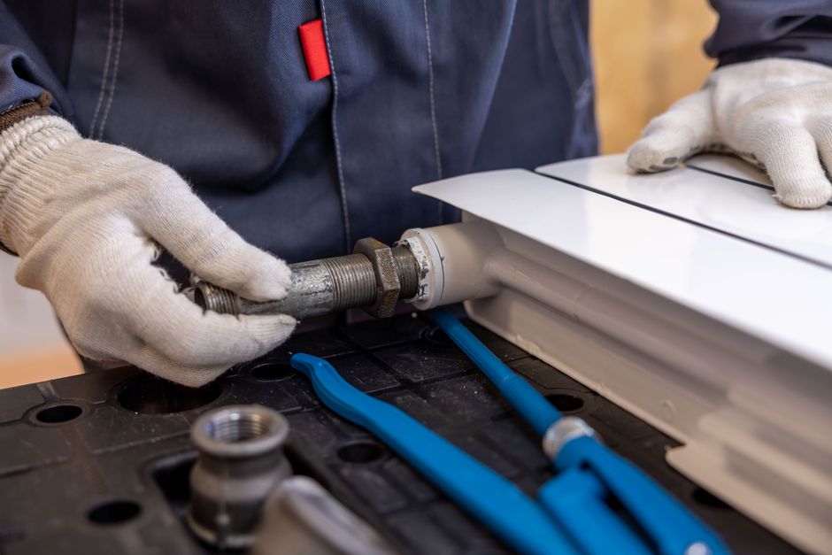 A plumber installing a radiator pipe with tools